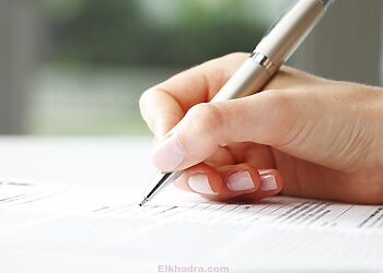 Businesswoman's hand with pen completing personal information on a form