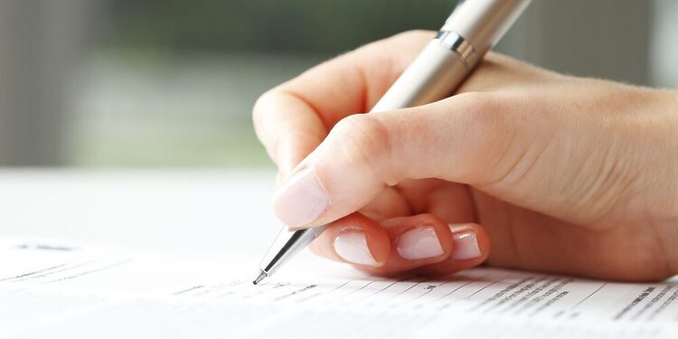 Businesswoman's hand with pen completing personal information on a form