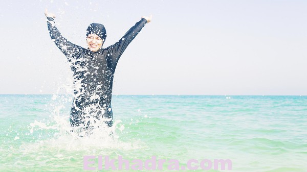 young woman in burkini splashing water